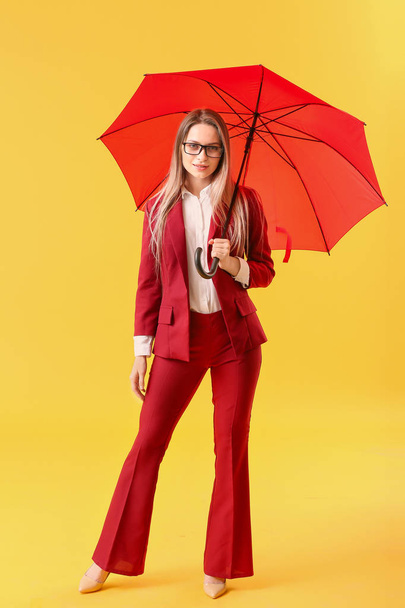 Beautiful businesswoman with umbrella on color background - 写真・画像