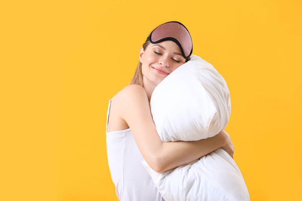 Молода жінка з подушкою та маскою для сну на кольоровому фоні
 - Фото, зображення
