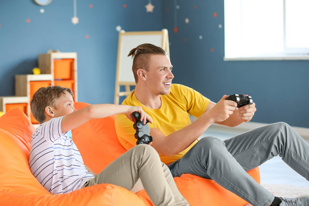 Πορτρέτο του πατέρα και του γιου παίζοντας βίντεο παιχνίδι στο σπίτι - Φωτογραφία, εικόνα