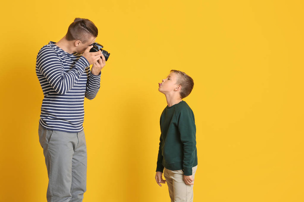 Padre tomando la foto de su pequeño hijo en el fondo de color
 - Foto, imagen