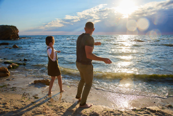 Liebespaar am Sonnenaufgang Strand wirft einen Stein ins Meer. schöne romantische Liebe Hintergrund - Foto, Bild