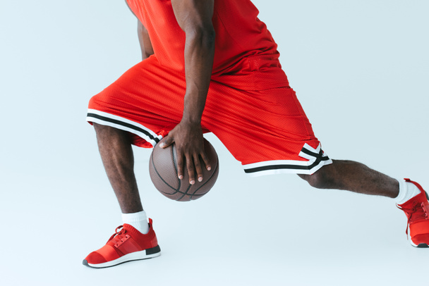 vista parcial del deportista afroamericano jugando baloncesto sobre fondo gris
 - Foto, imagen