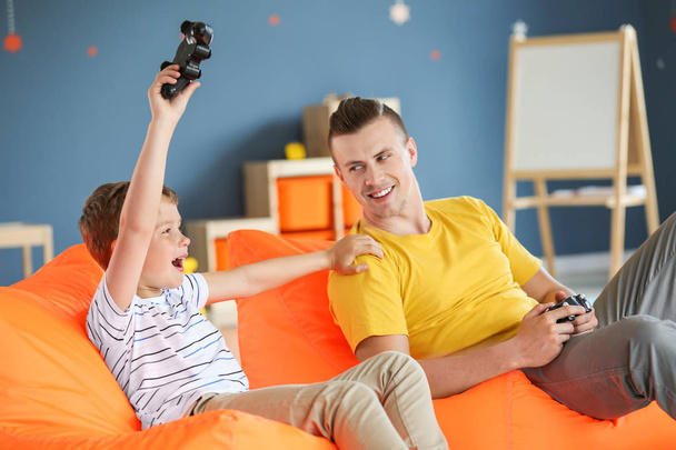 Retrato de padre e hijo jugando videojuegos en casa
 - Foto, Imagen