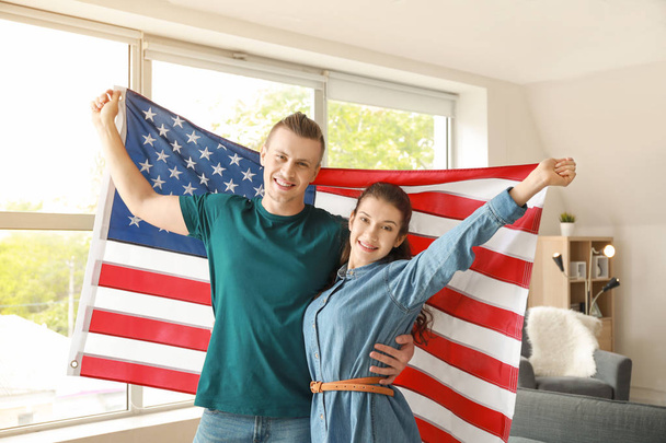 Young couple with USA flag at home. Independence Day celebration - 写真・画像