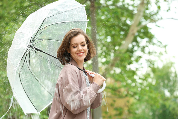 Beautiful young woman with umbrella outdoors on rainy day - Foto, immagini