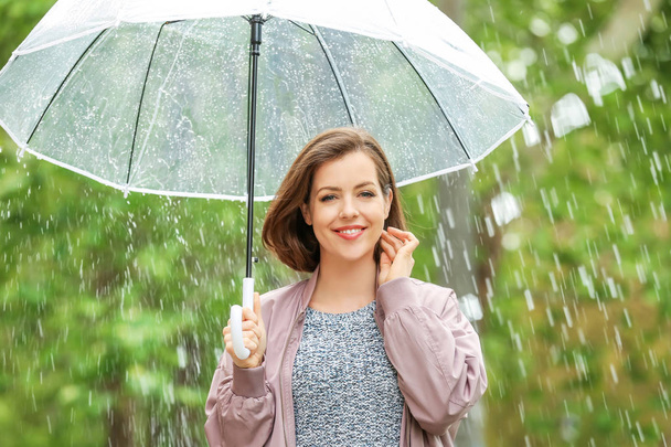 Όμορφη νεαρή γυναίκα με ομπρέλα σε εξωτερικούς χώρους σε βροχερή ημέρα - Φωτογραφία, εικόνα