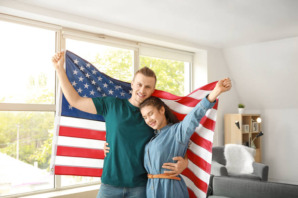 Young couple with USA flag at home. Independence Day celebration - Photo, Image