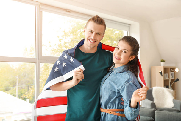 Young couple with USA flag at home. Independence Day celebration - Zdjęcie, obraz