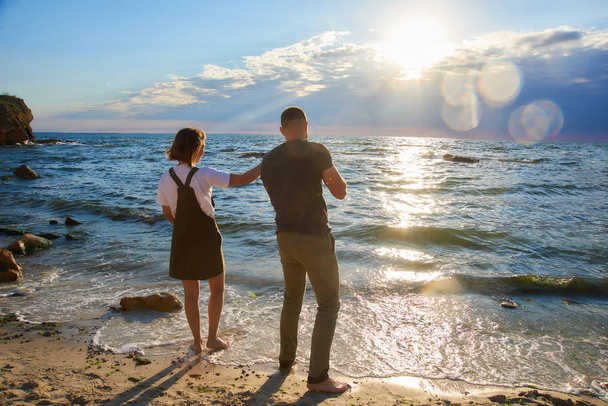 Liebespaar am Sonnenaufgang Strand wirft einen Stein ins Meer. schöne romantische Liebe Hintergrund - Foto, Bild