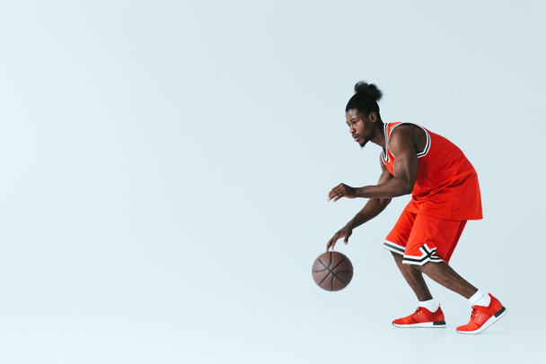 コピースペースで灰色の背景にバスケットボールをプレイハンサムなアフリカ系アメリカ人のスポーツマン - 写真・画像