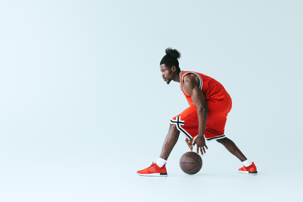 atletický afroamerický sportovec hrající basketbal na šedém pozadí - Fotografie, Obrázek