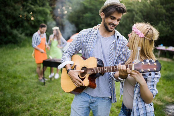 Group of friends having outdoor barbecue laughing together - Foto, imagen