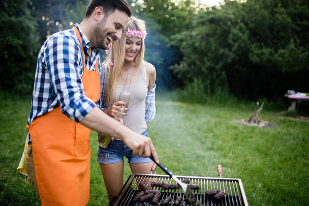 Friends making a barbecue together outdoors in the nature - Photo, image