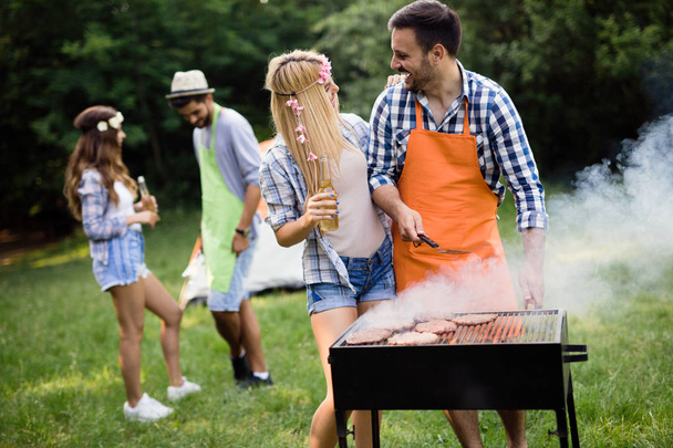 Friends making a barbecue together outdoors in the nature - Photo, Image