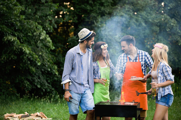 Group of friends having outdoor barbecue laughing together - Foto, Imagen