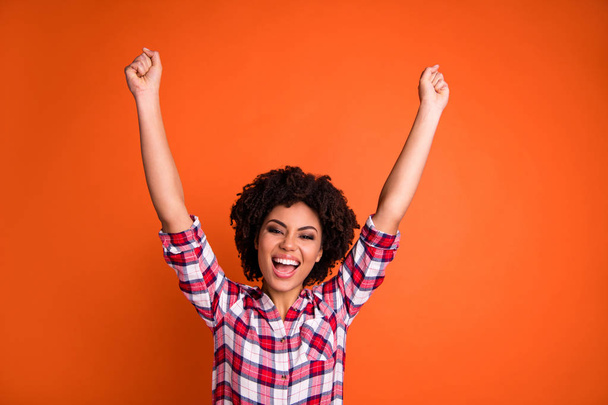 Portrait of her she nice attractive ecstatic cheerful cheery wavy-haired lady wearing checked shirt raising hands up winning victory triumph isolated over bright vivid shine orange background - Foto, afbeelding