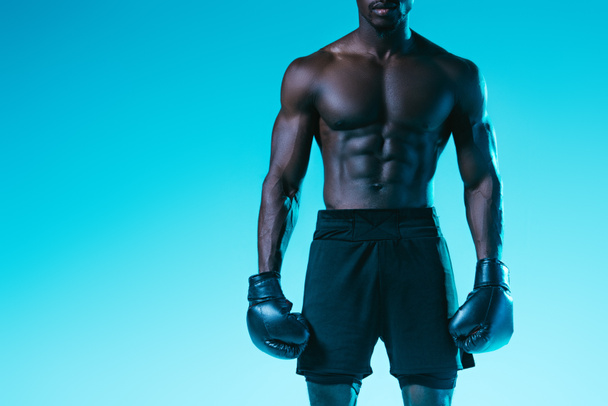 vista recortada del deportista afroamericano en guantes de boxeo sobre fondo azul
 - Foto, Imagen