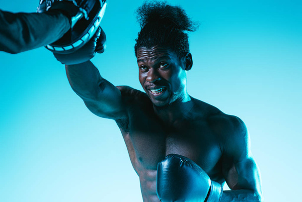 muscular african american boxer working out with trainer on blue background - Fotografie, Obrázek