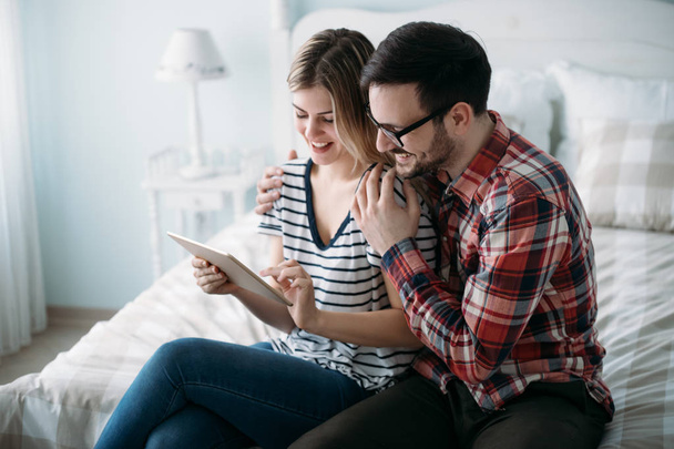 Young happy couple using digital tablet in bedroom - Foto, Imagen