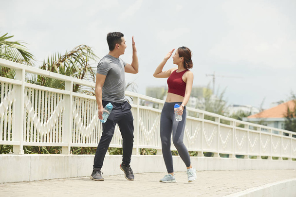 Excited joggers giving each other high five after training outdoors - Photo, Image