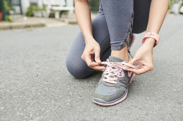 Imagen de cerca de la mujer atando cordones de zapatos antes de correr al aire libre
 - Foto, imagen