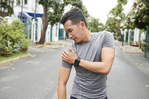 Young Asian man dislocated shoulder when training outdoors - 写真・画像