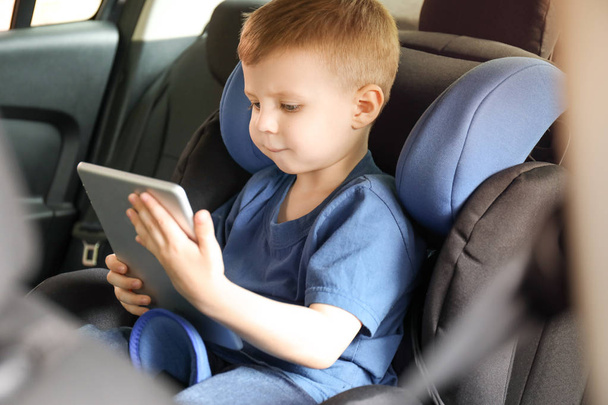 車の座席に座ってタブレットコンピュータを持つ小さな男の子 - 写真・画像