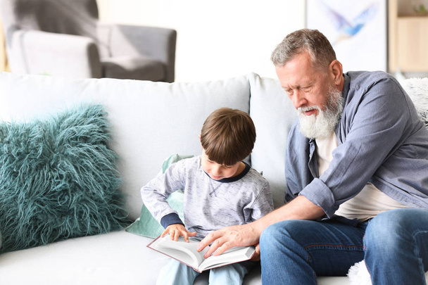 Cute little boy with grandfather reading book at home - Foto, Imagem