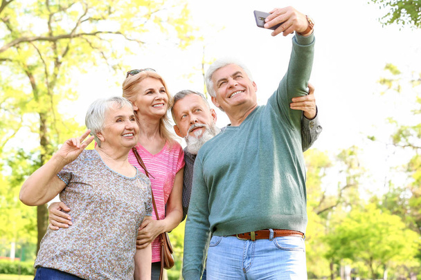 Ryhmä onnellisia vanhuksia ottaa selfie puistossa
 - Valokuva, kuva