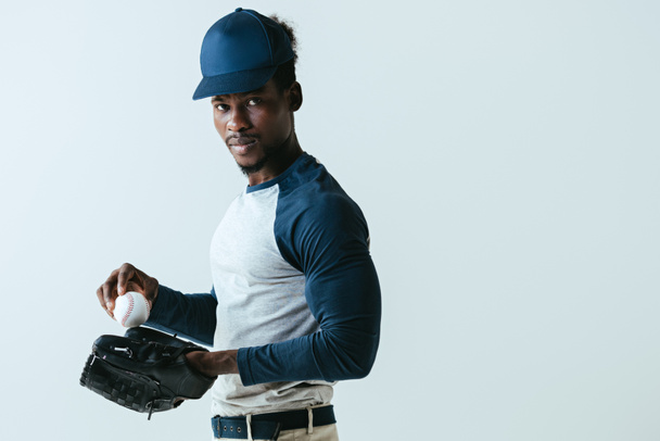vertrouwen African American sportman in honkbal handschoen kijken naar camera geïsoleerd op grijs - Foto, afbeelding