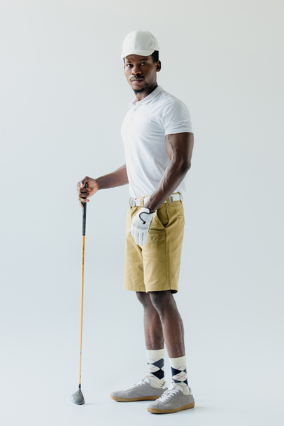 handsome african american sportsman holding golf club on grey background - Foto, afbeelding