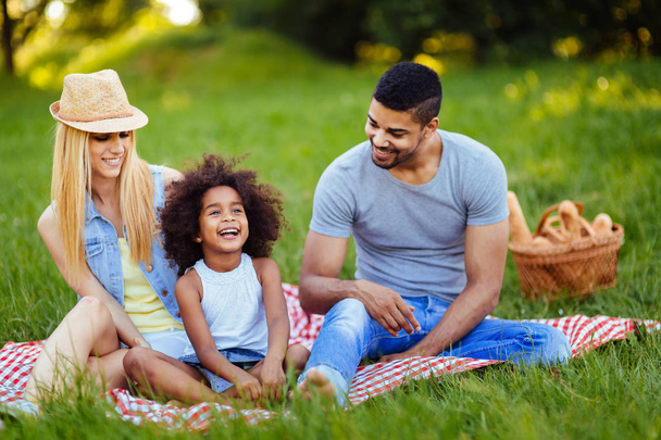 Picture of lovely couple with their daughter having picnic in nature - Фото, зображення