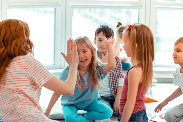 Cute positive girl giving high five to the teacher - Foto, immagini
