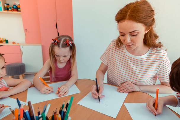 Nice pleasant woman drawing together with kids - Photo, image
