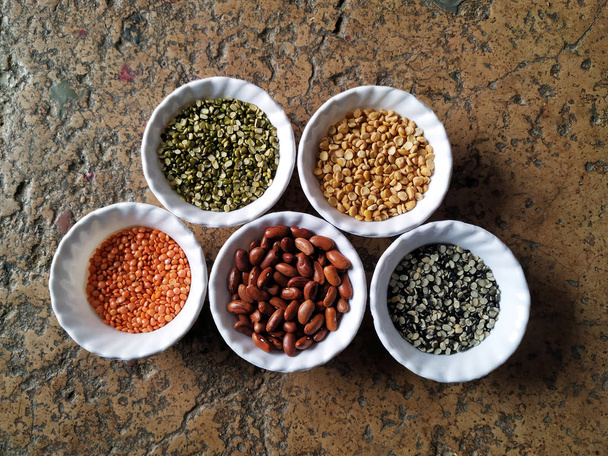 Leguminosas não cozidas, grãos e sementes em taças brancas sobre fundo branco. foco seletivo
 - Foto, Imagem