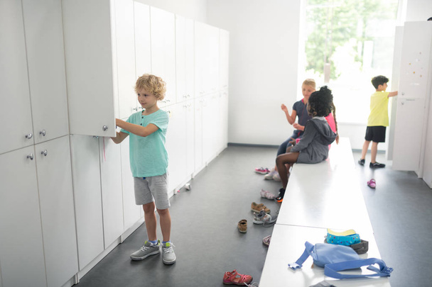 Children in a changing room preparing for sports. - Фото, изображение