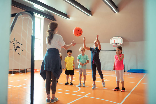 Children playing ball with their coach at sports class. - Фото, изображение