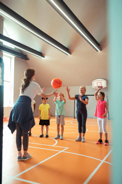 Sports teacher throwing ball to her pupils. - Fotó, kép