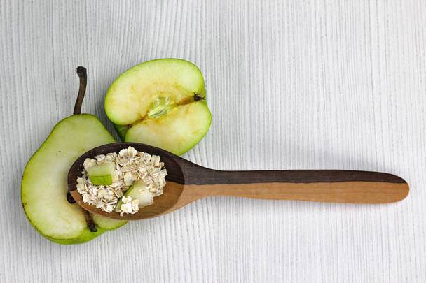 lepel met havermout en stukjes appel en peer, voedzaam ontbijt voedsel gezonde havermout  - Foto, afbeelding