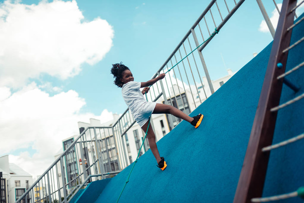 Smiling girl climbing up on a sports ground. - Foto, afbeelding