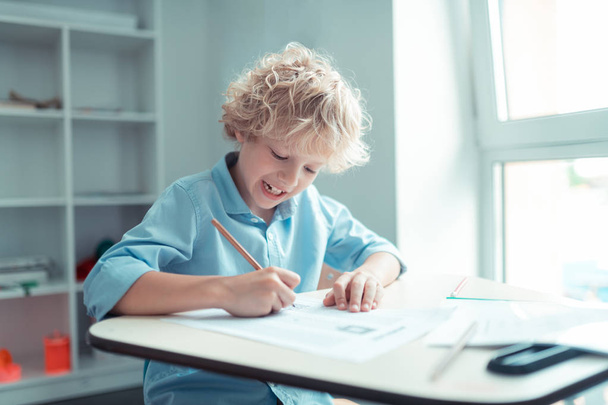 Cheerful pupil finishing his test in maths. - Foto, Bild