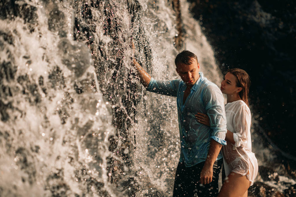 Casal abraçando sob os riachos de uma cachoeira
. - Foto, Imagem