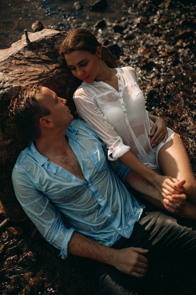 Una pareja sentada junto a la roca y cogida de la mano
. - Foto, Imagen