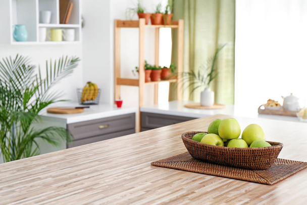 Wicker bowl with apples on table in modern kitchen - Foto, immagini