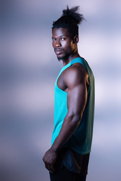 handsome, muscular african american sportsman posing at camera on grey background with lighting - Fotografie, Obrázek