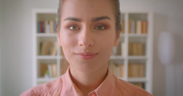 Closeup portrait of young pretty female student looking at camera smiling cheerfully in the college library - Filmagem, Vídeo