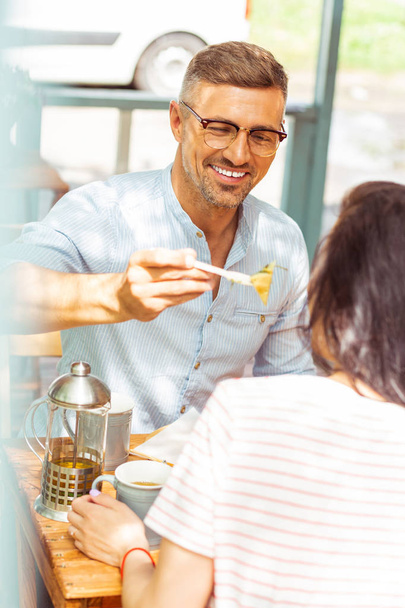 Smiling man sharing his food with his wife. - Фото, зображення