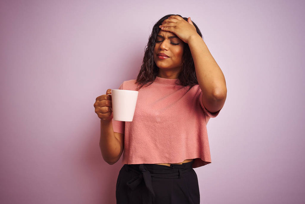 Транссексуальна транссексуальна жінка п'є чашку кави над ізольованим рожевим тлом, напруженим рукою на голові, шокованим соромом і несподіваним обличчям, розлюченим і розчарованим. Страх і засмучення за помилку
. - Фото, зображення