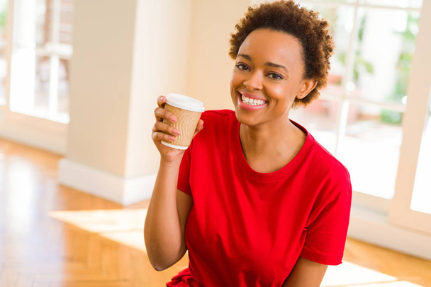 Beautiful young african american woman drinking a coffee in a ta - Foto, afbeelding