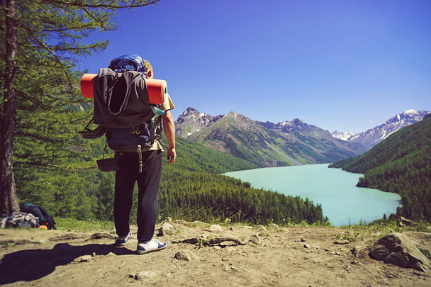 Homme voyageur avec sac à dos alpinisme Voyage Lifestyle concept. Backpacker avec un grand sac à dos regarde la vallée de montagne avec un beau lac vert. Admirer la nature
 - Photo, image